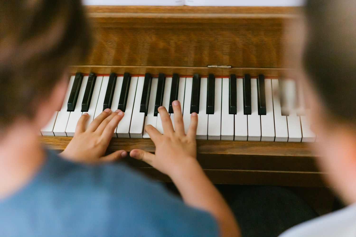 Student hands on piano next to teacher